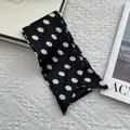 Close-up of a French vintage black silk scarf with white polka dots on a textured fabric - Large Polka Dot Black