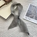 Detailed view of gray linen skinny scarf tied in a knot on a textured fabric surface - Gray