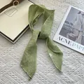 Macro detail of grass green ramie scarf showing natural fiber texture and care label - Green