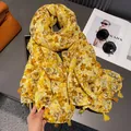 Detail of yellow floral scarf with tassels next to orange bag and sunglasses - Yellow