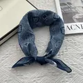 Sciarpa blu con motivi geometrici e floreali presentata su uno sfondo bianco trapuntato - Blu navy