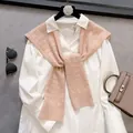 Flat lay of white shirt and pink cable knit shawl with premium texture and accessories - Nude Pink