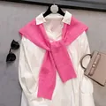 Detailed view of pink cable-knit sweater shawl styled over a white button-down shirt - Rose Red