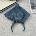 Detalle del pañuelo triangular de algodón y lino azul con bordes remallados y flores pequeñas - Azul Retro