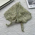 Gros plan du foulard triangle en coton et lin avec motif floral et finitions soignées - Vert