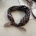 Detail van een vintage bruine geruite halsdoek geknoopt in een strik op zachte stof - Camel Geruit