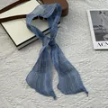 Close-up of lightweight blue plaid linen scarf with fine hemmed edges on white texture - Blue