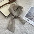 Detail showing natural linen texture of a striped beige and brown scarf on magazine - Striped