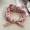 Dettaglio di un foulard rosa in cotone con motivo a ciliegie annodato su fondo bianco - Piccola Ciliegia