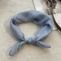 Detail of light blue checkered cotton scarf tied in a knot on soft white texture - 58*58cm / Plaid Blue