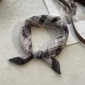 Detail van geruite zijden sjaal met zachte stoftextuur en geknoopte styling op wit tapijt - Kant Beige
