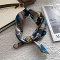 Detalle de pañuelo de seda con bordes dorados sobre un fondo de tela blanca texturizada - Azul