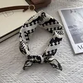 Detailansicht eines geknoteten Seidentuchs mit schwarzem Wellenrand und geometrischem Muster - Schwarz-Weiß Geometrisches Muster / Schwarz