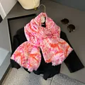 Detail eines rosa-orangefarbenen Batik-Schals mit Fransen an einem modischen Kleiderbügel - Rosa
