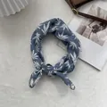 Close-up of blue linen scarf featuring white leaf patterns and delicate grey lace edges - Bandana / Blue