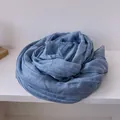 Close-up of soft dusty blue cotton linen scarf with elegant lace trim details - Blue