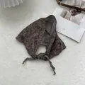 Dettaglio di sciarpa in lino marrone vintage con fiori neri e fodera a quadretti classici - caffè