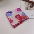 Detail eines geblümten Baumwolltuches mit bunten Handmalereien und roter Overlock-Nahtkante - Halo Floral