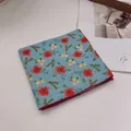 Detail eines blauen Baumwoll-Bandanas mit Blumenmuster und roten Rollsaumkanten - Sonnenblume