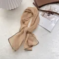 Dettaglio di sciarpa in seta color albicocca con bordi neri ondulati su peluche bianco - 105*47cm / Cachi