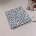 Detail showing folded cotton linen bandana with vintage floral pattern on soft background - Malt Green