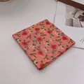 Detail eines weichen Baumwoll-Bandanas mit korallenrosa Stoff und kleinem Blumenmuster - Gänseblümchen