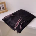 Detail of black cotton linen scarf showing pleated texture and colorful tassel fringe - Black