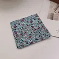 Detail of light blue floral cotton linen bandana folded on a white textured background - Little Floral
