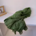 Close-up of dark green linen scarf with polka dots and frayed edge detail - Green