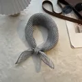 Foulard in puro lino a righe bianche e nere annodato su uno sfondo materico morbido - Stile a Costine Sottili