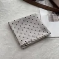Primer plano de pañuelo de algodón beige con lunares y borde detallado sobre fondo suave - Caqui