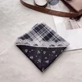 Detail of folded square scarf featuring floral prints, lace patterns, and classic blue checks - Black Lace Plaid