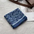 Detail of blue cotton linen headscarf with white floral print on cream textile - Tree Branch