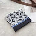 Detail of rose floral print cotton bandana with blue stripe and black border on plush rug - Black Edge Tiny Floral
