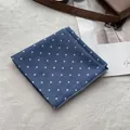 Detailed view of blue polka dot cotton scarf on a white plush background with accessories - Teal