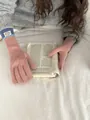 Close-up of pink knit gloves with blue ribbed cuffs and brand label on white bedding - Pink + Blue