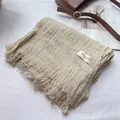 Detailed texture of off-white crinkled linen scarf with natural frayed edges and label - Off White