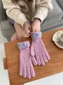 Detailansicht der rosa Strickhandschuhe mit ERET-Markenetikett auf einem Holztisch - Lila