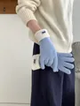 Detailaufnahme von Strickhandschuhen mit hellblauem Körper, cremefarbenen Bündchen und Label - Himmelblau