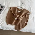 Detail of milk tea knit shawl showing thick waffle texture and chic tie straps - Camel