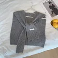 Detalle de chal de punto gris oscuro con textura de gofre y lazo decorativo - Gris