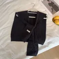 Vista detallada de chal negro de punto trenzado con diseño de lazo frontal - Negro