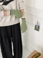 Close-up of green and beige knitted gloves with a woven label on the long cuffs - Bean Green and Beige