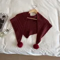 Detailed texture of burgundy knitted shawl with large soft pom-poms on wooden hanger - Ancorra Red