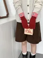 Details von roten Strickhandschuhen mit rosa Umschlagmanschetten und blauem Webetikett - Rot