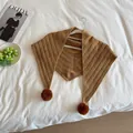 Close-up of brown knit triangle scarf with soft pom-poms and delicate hollow textures - Caramel color