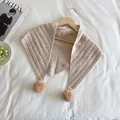 Detail of knit triangle shawl with hollow stripes and soft pom-pom on wooden hanger - Off White