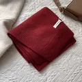 Primer plano de bufanda roja de lana 100% pura mostrando textura de punto y la etiqueta - Rojo Ancorra