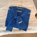 Primer plano de chal de punto azul con textura de cuadros y etiqueta de marca en percha - Azul