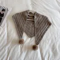 Detailed knit texture of brown shawl with soft pom-poms on a white background - Camel